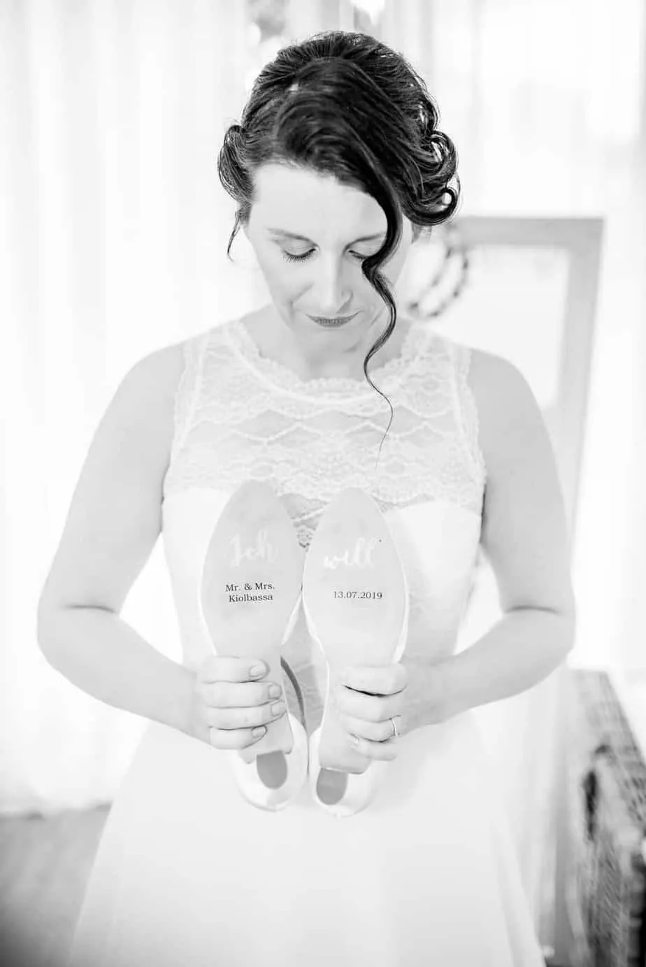 Braut Steffi hält ihre beschrifteten Brautschuhe vor der Hochzeit