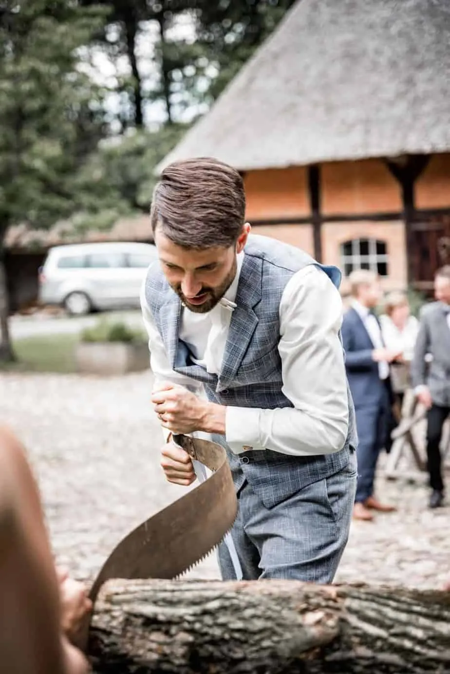 Bräutigam beim Baumstammsägen nach der Trauung