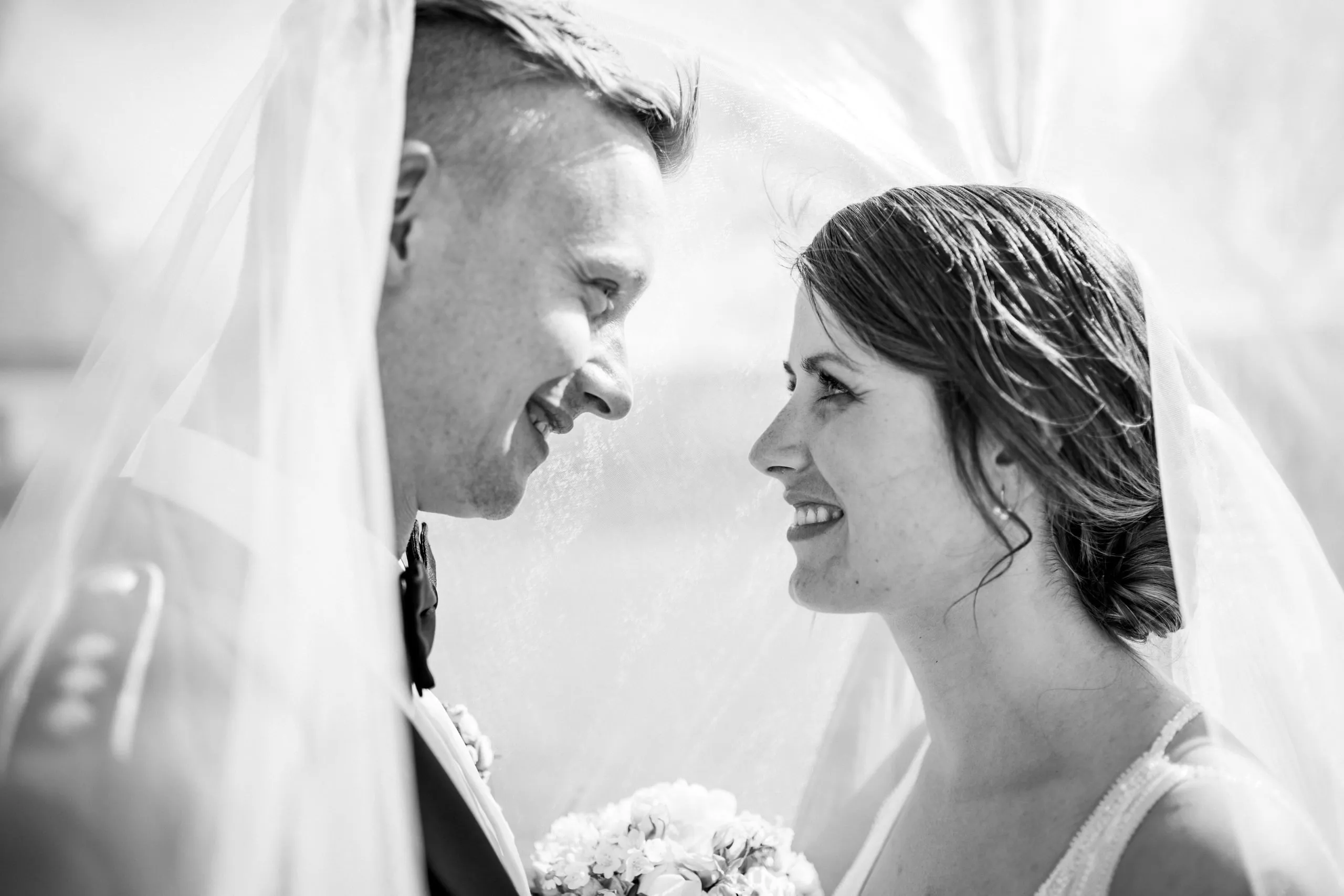 Valerie und Tim lachen gemeinsam unter dem Brautschleier