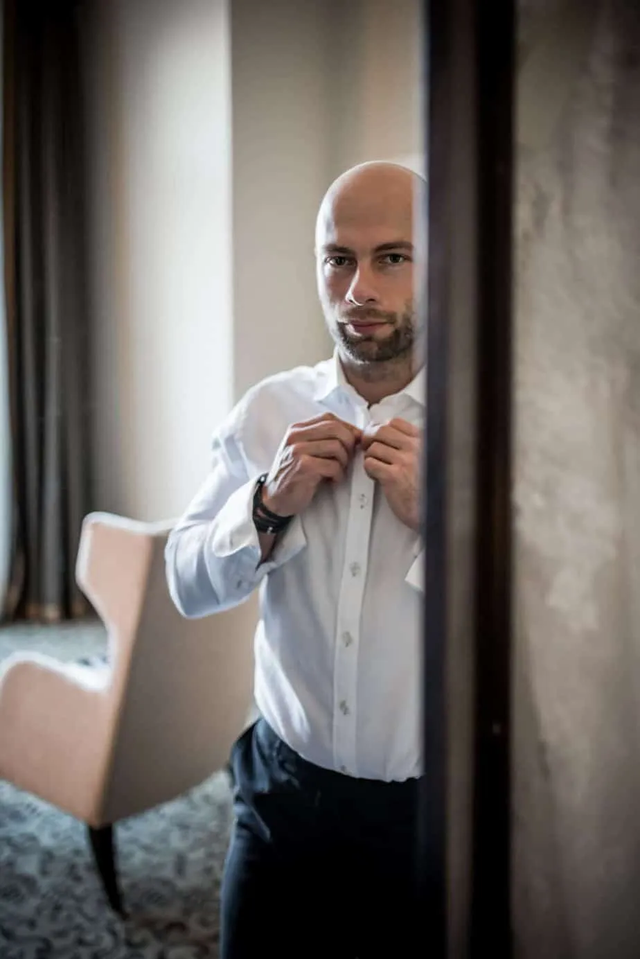 Bräutigam beim Anlegen der Manschettenknöpfe in seiner Hotelsuite