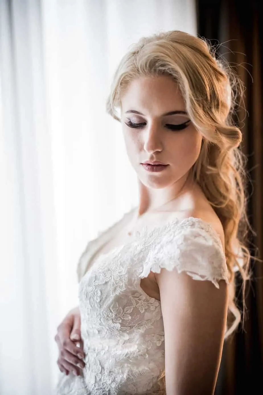 Braut im Spitzenkleid während des Getting Ready