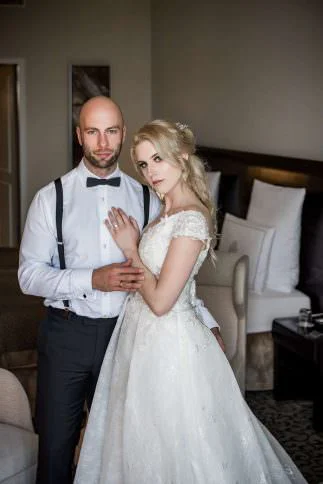 Brautpaar im Hotelzimmer: Braut im Spitzenkleid und Bräutigam mit Fliege
