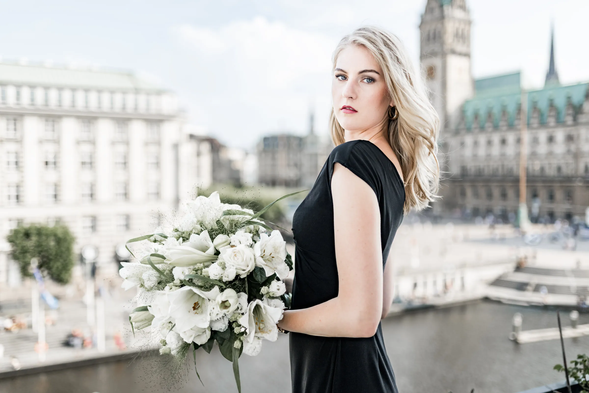 Editorial Portrait einer Frau mit weißem Blumenstrauß vor dem Hamburger Rathaus
