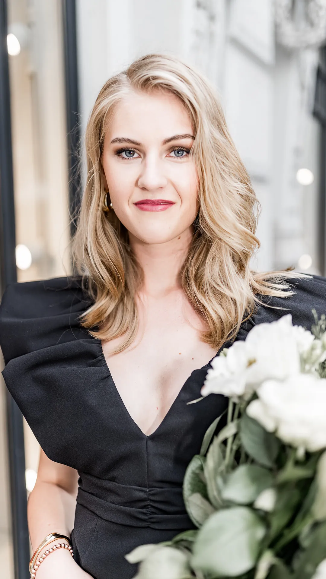 Nahes Editorial Portrait einer Frau im schwarzen Kleid mit weißem Blumenstrauß in Hamburg