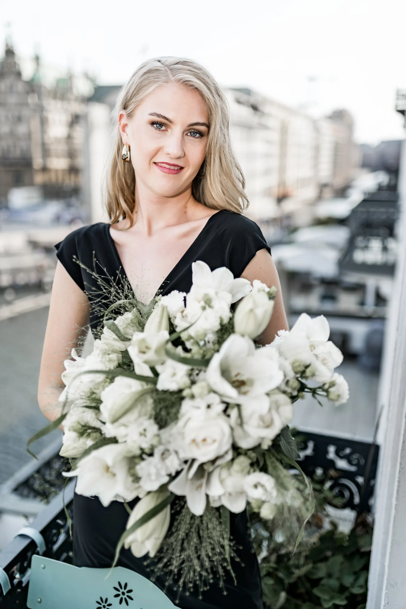 Lächelndes Editorial Portrait einer Frau mit weißem Blumenstrauß über den Dächern Hamburgs