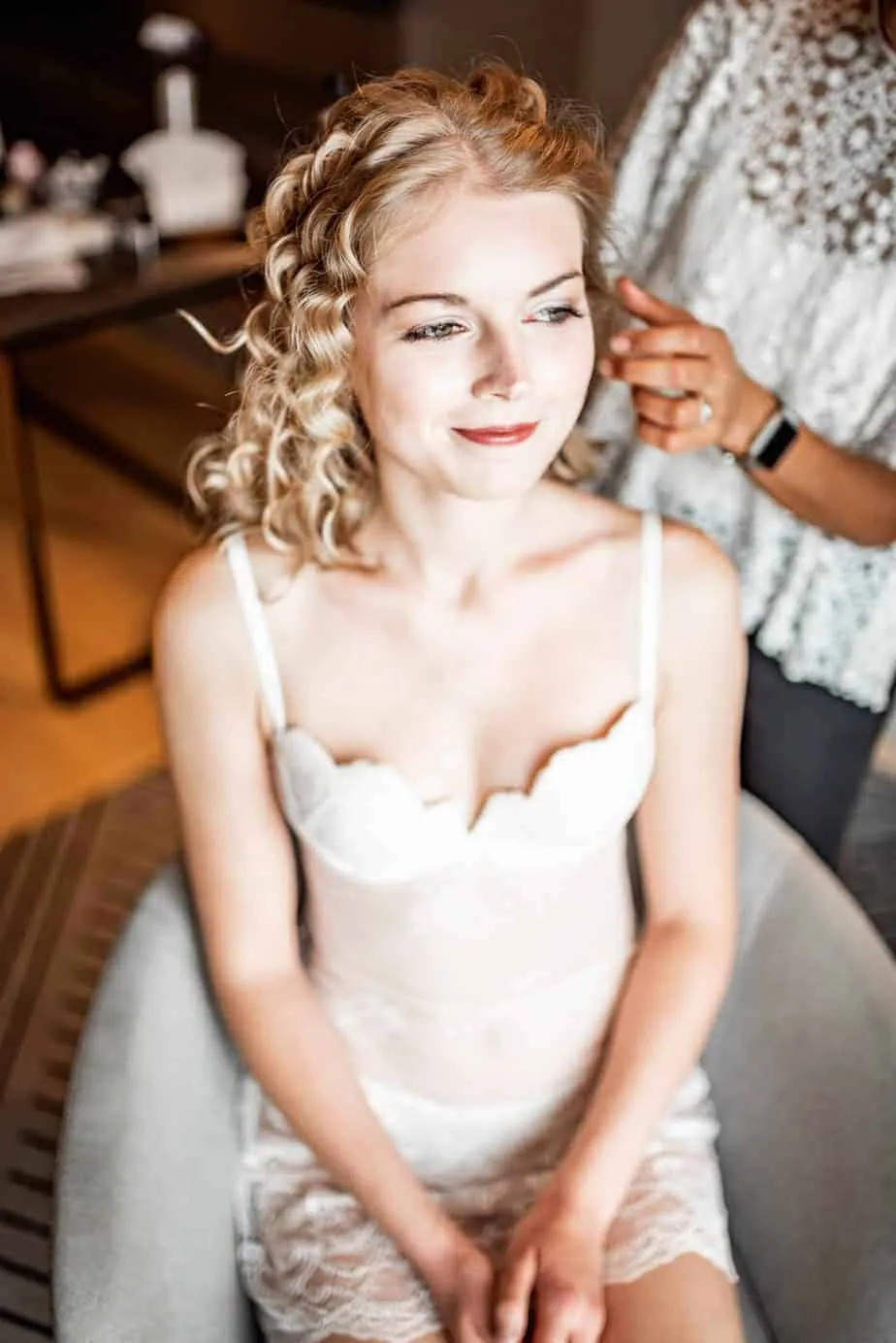 Stylistin richtet die Locken der Braut am Hochzeitsmorgen
