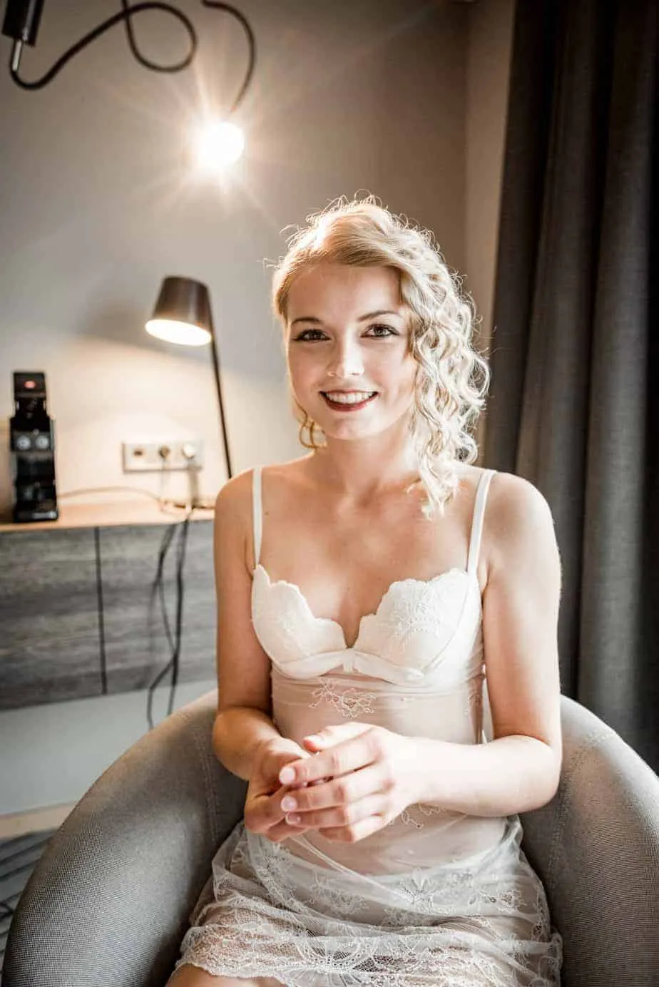 Lachende Braut in weißer Hochzeitswäsche nach dem Styling