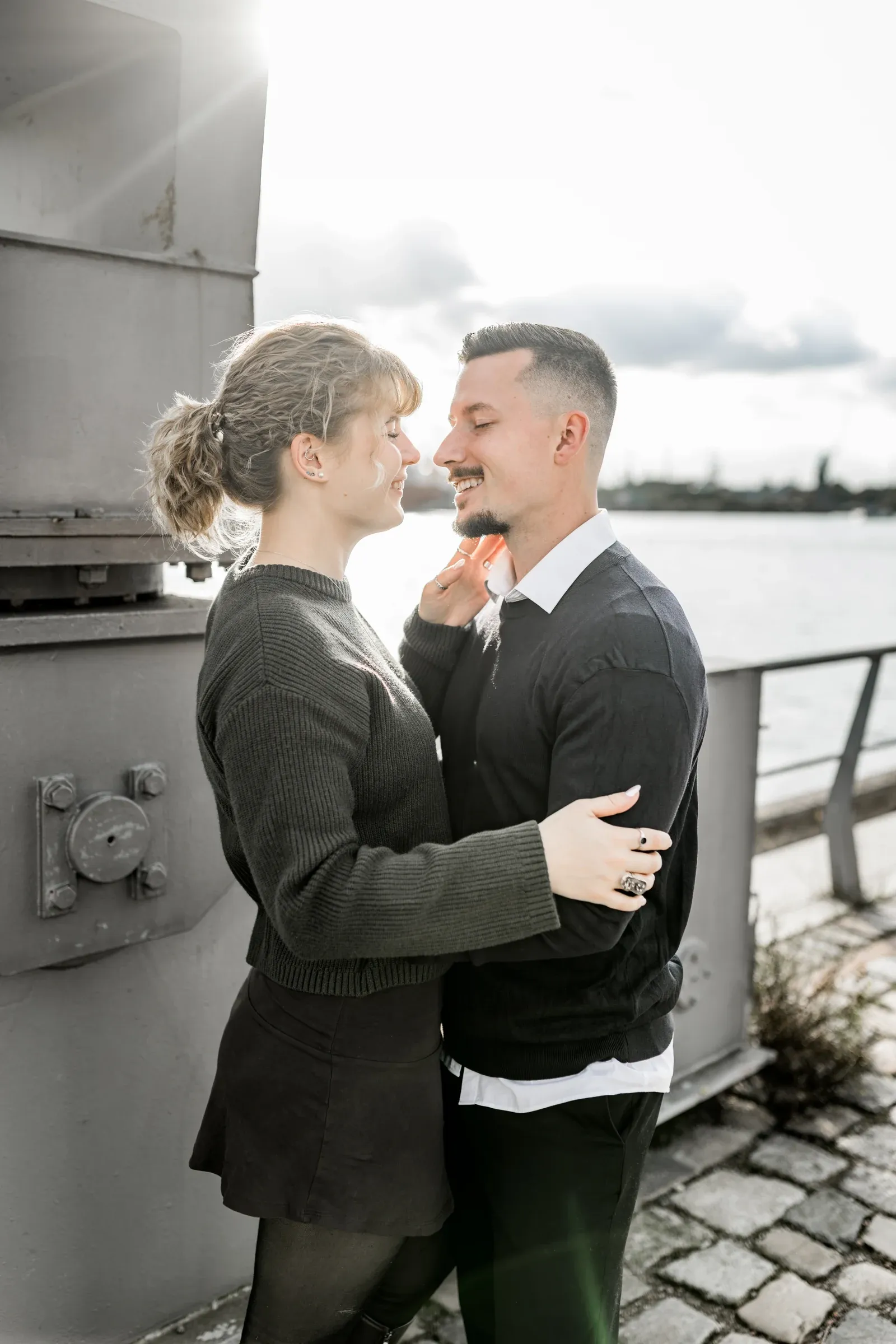 Liza und Domenic umarmen sich im Gegenlicht neben einer HafenCityfassade