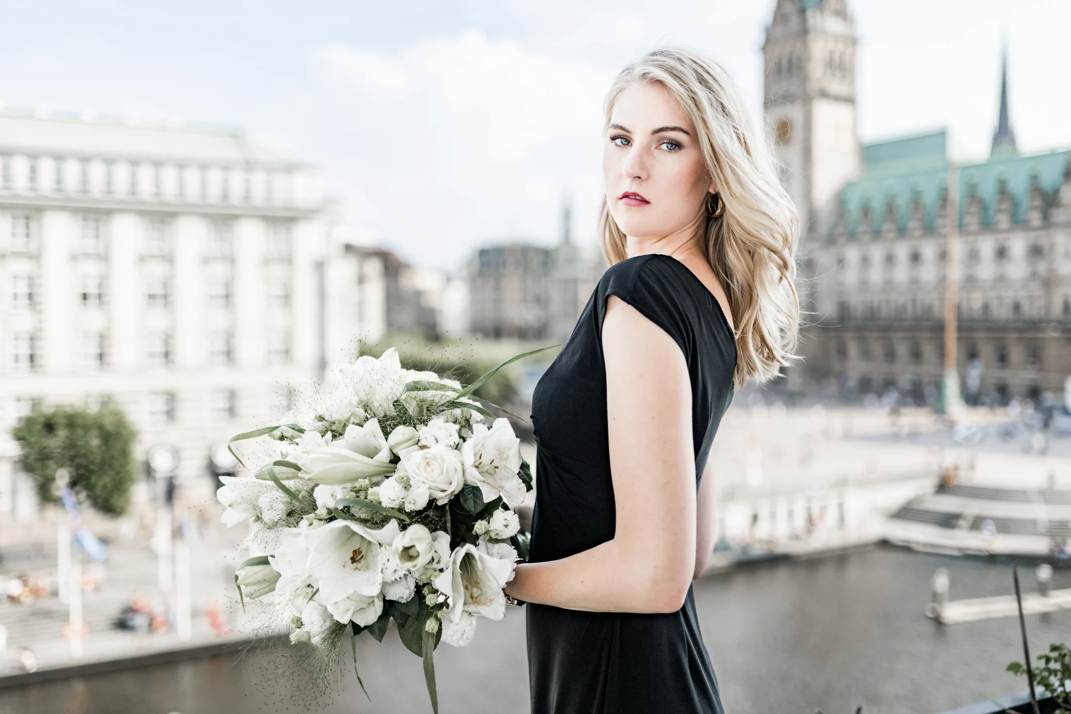 Porträt einer Frau mit weißem Blumenstrauß vor dem Hamburger Rathaus