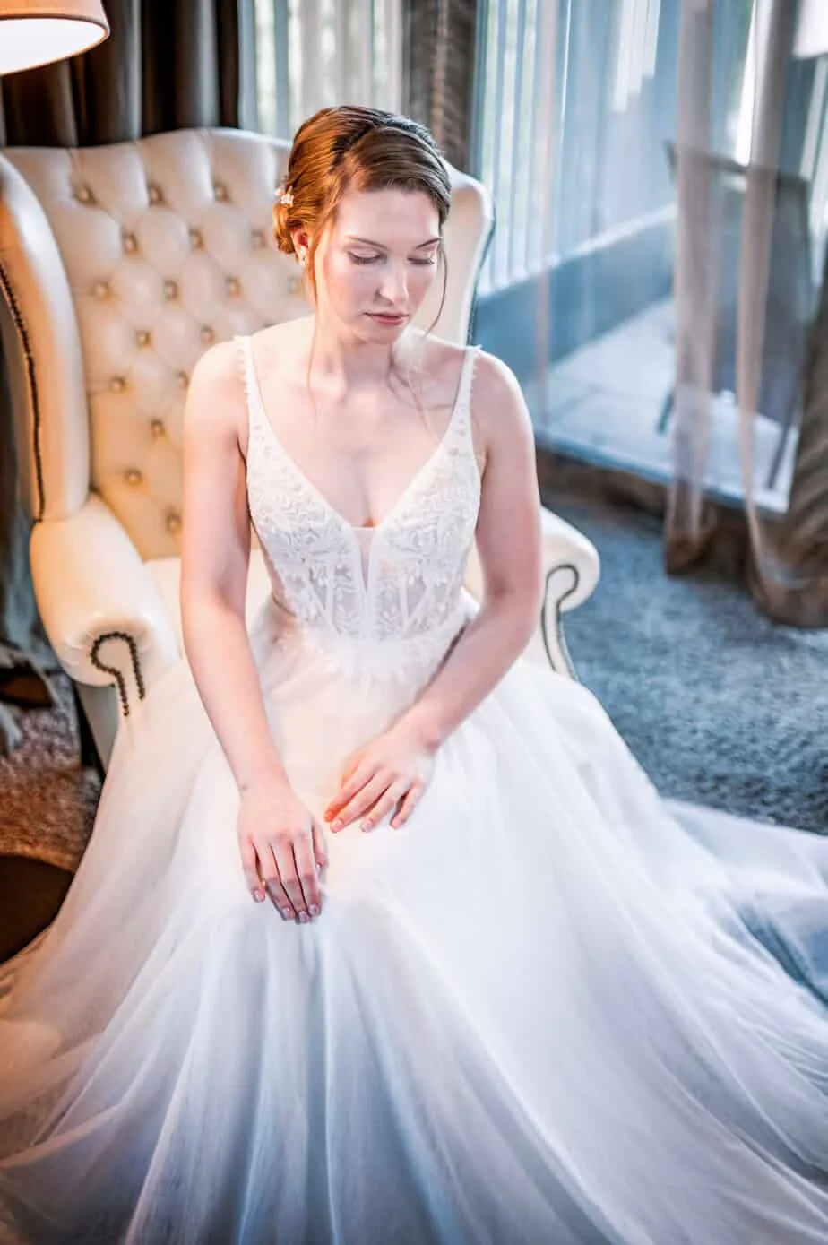 Braut sitzt im Brautkleid in einem Sessel der Hotelsuite