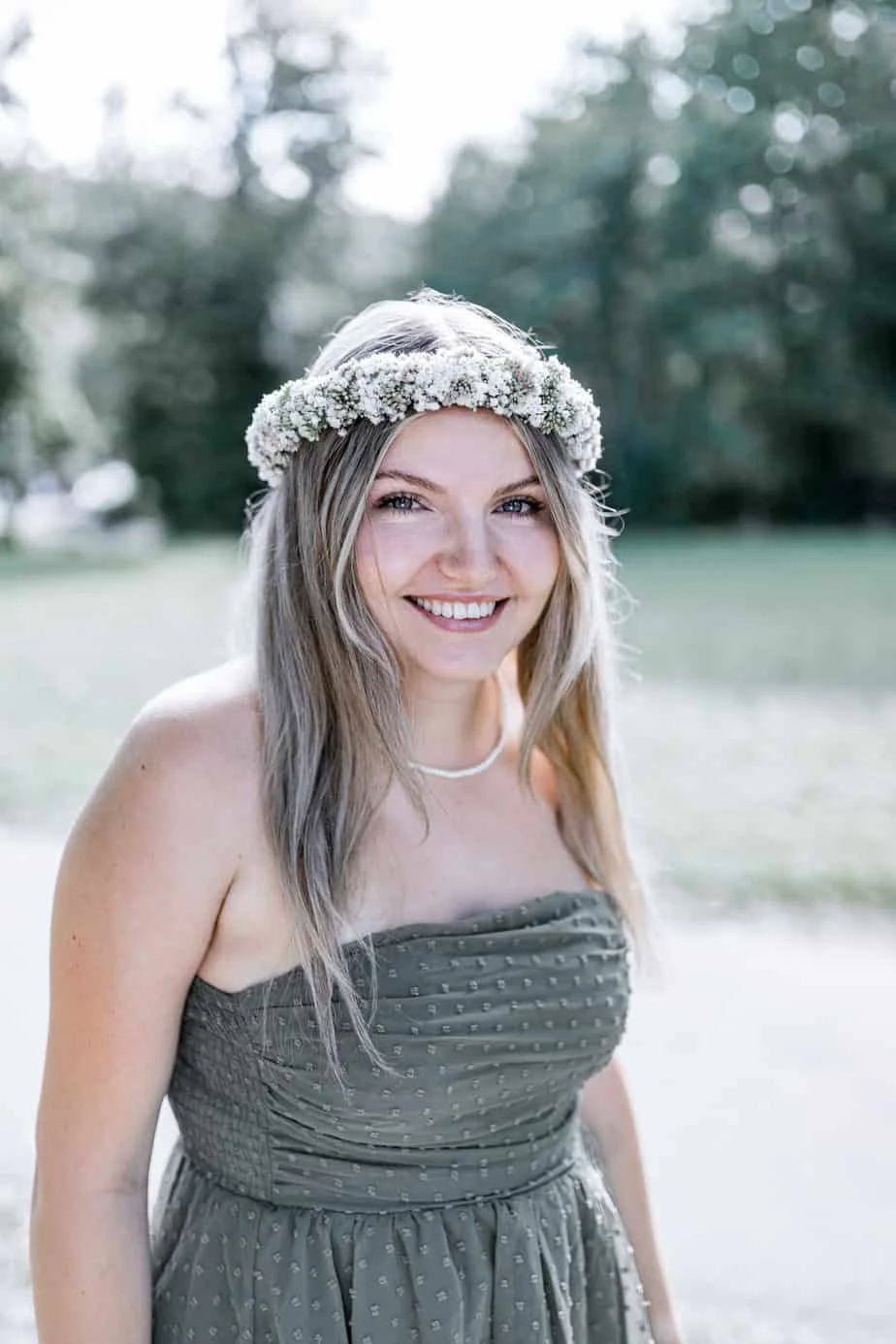 Lachende junge Frau mit Blumenkranz im weichen Abendlicht