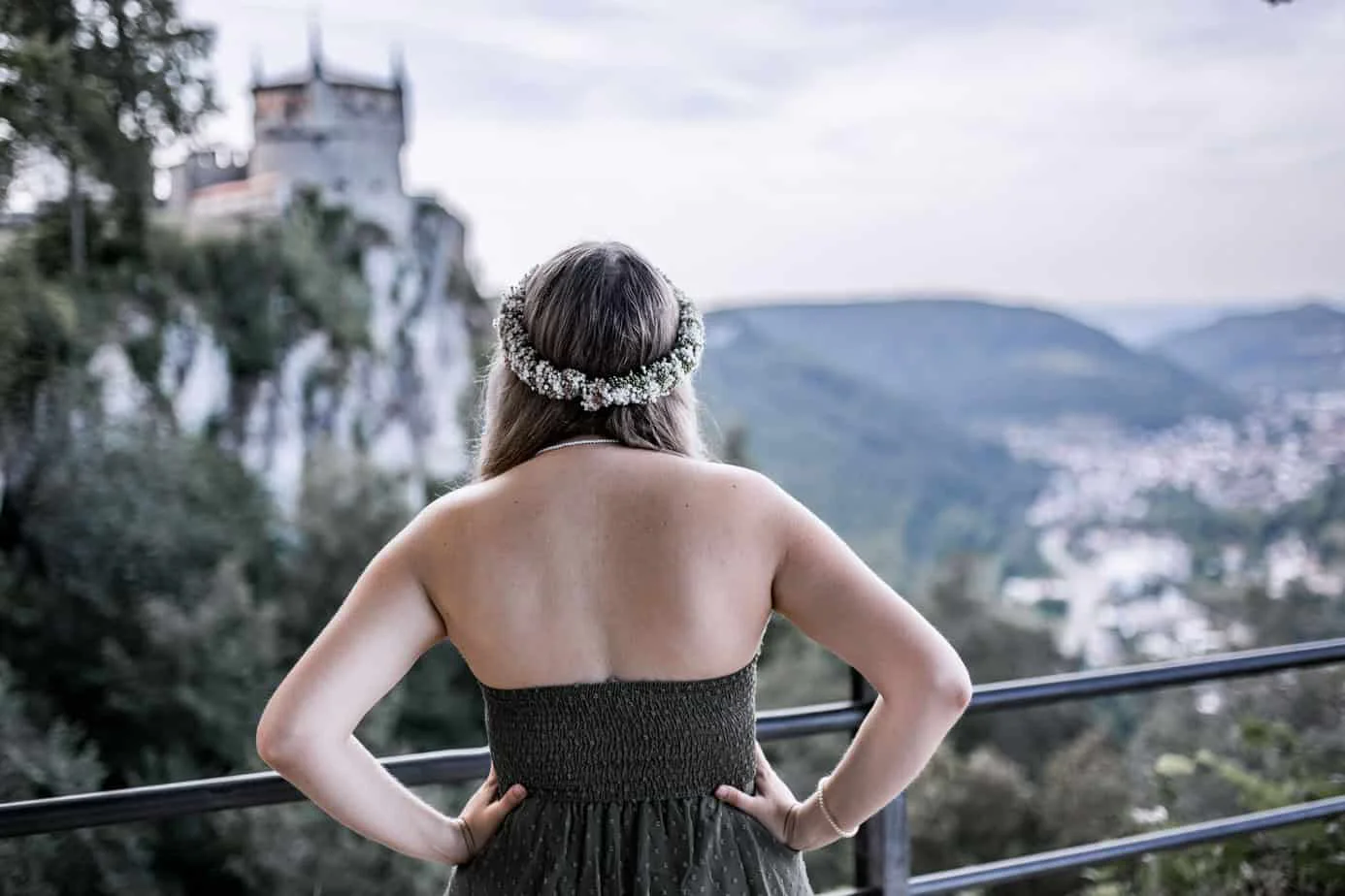 Frau mit Blumenkranz blickt von einem Aussichtspunkt auf Schloss Lichtenstein