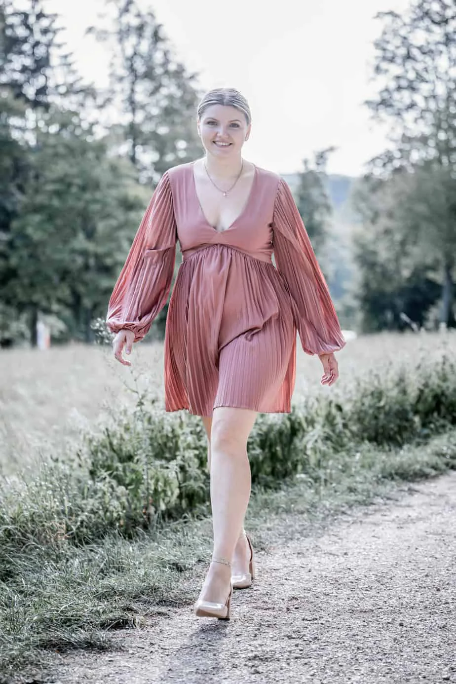Junge Frau im rosafarbenen Kleid auf einem Waldweg