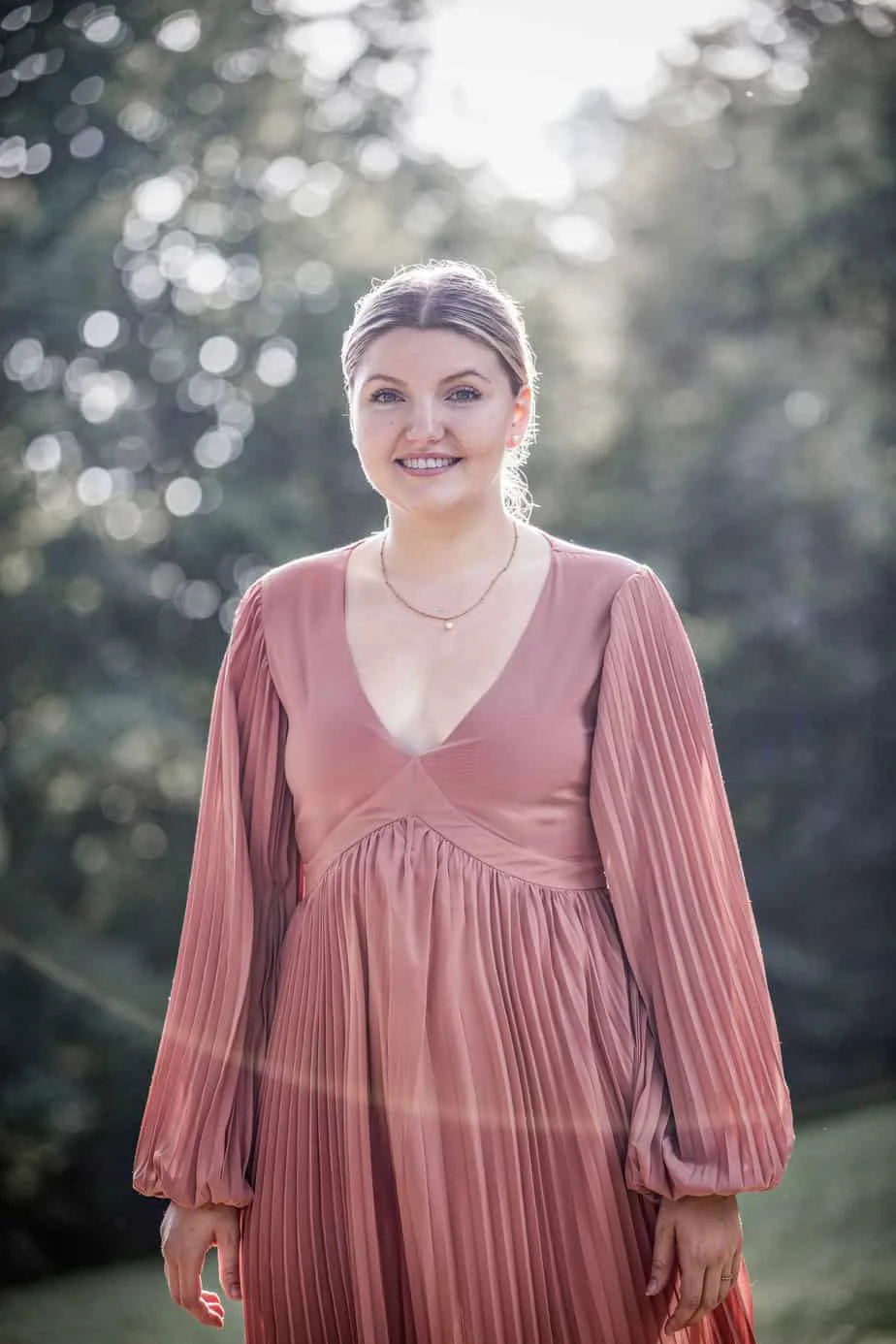 Portrait einer jungen Frau im rosafarbenen Kleid im Gegenlicht