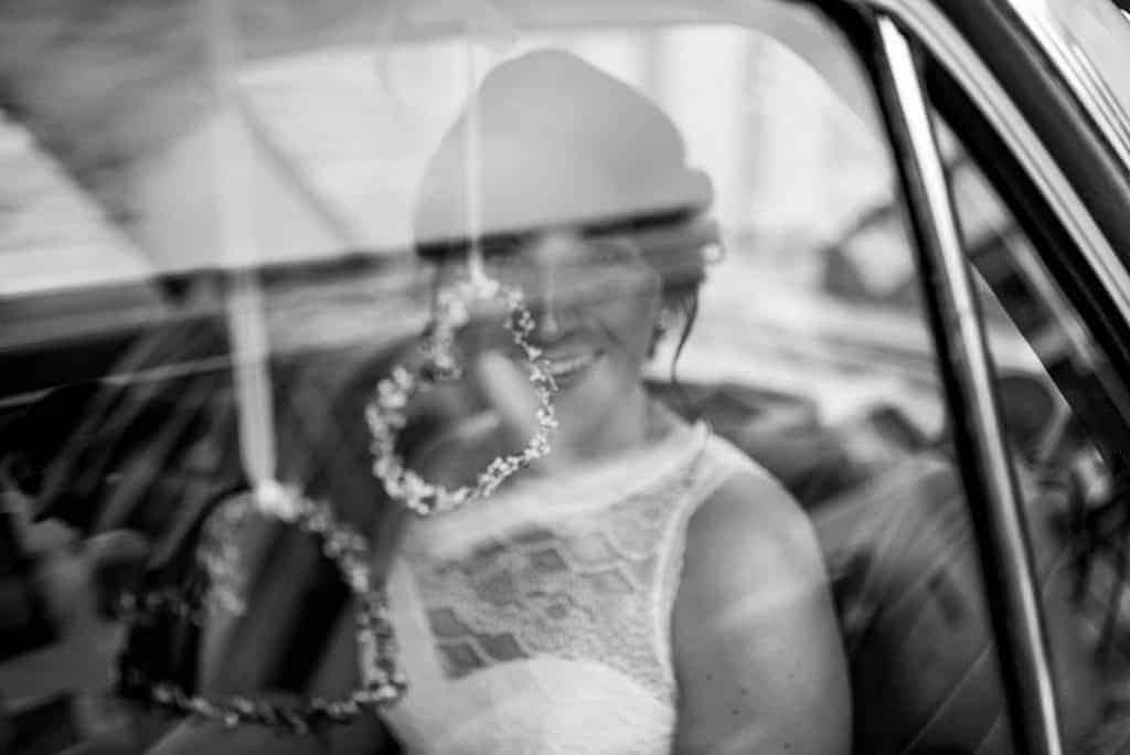 Braut schaut durch die Scheibe im Hochzeitsauto