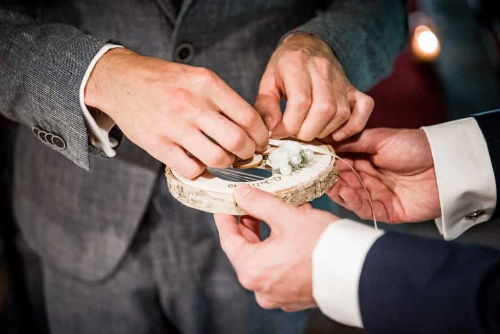 Bräutigam nimmt Ehering vom Baumstamm