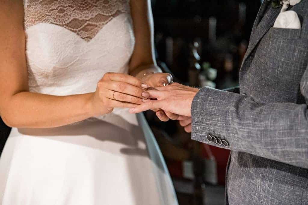 Braut steckt Ring auf den Finger vom Bräutigam