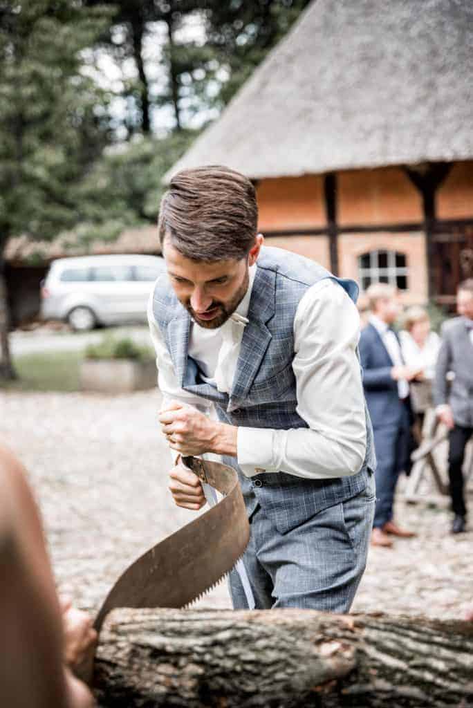 Bräutigam mit sich biegender Säge beim Holz sägen