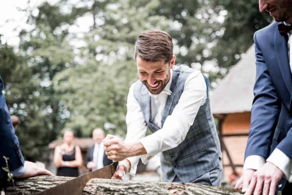 Bräutigam lächelt beim Sägen