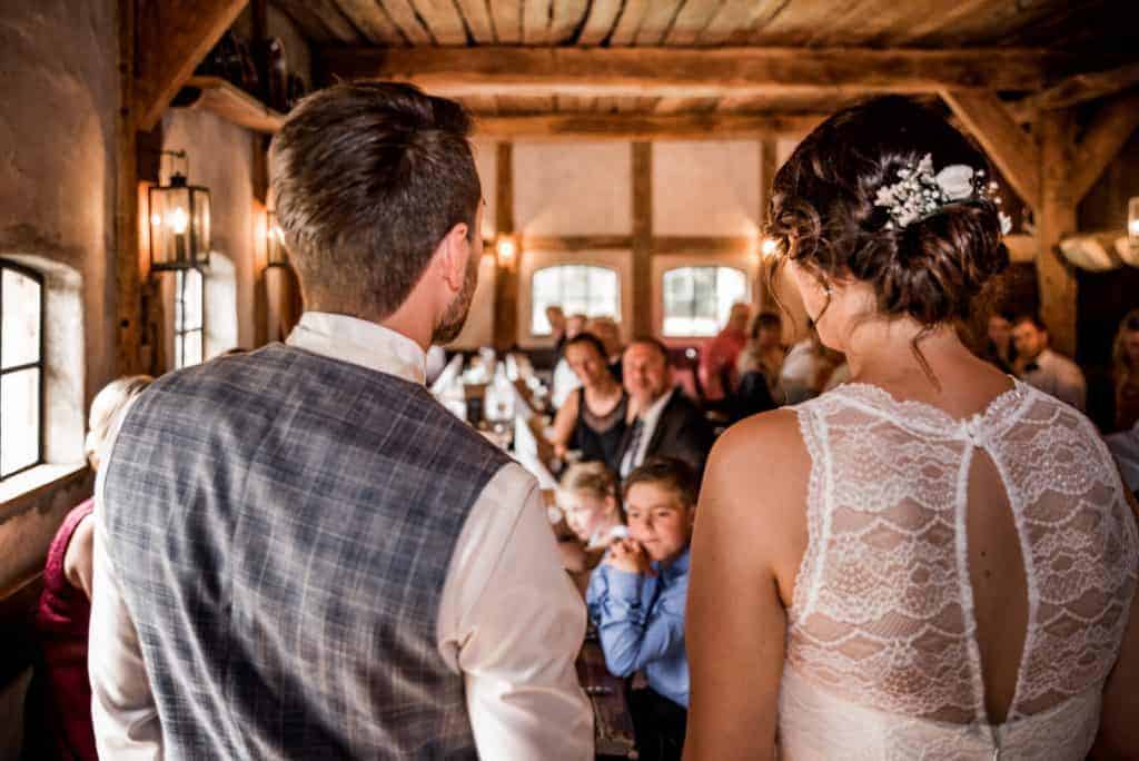 Brqautpaar spriucht zu den Gästen in einer Scheune
