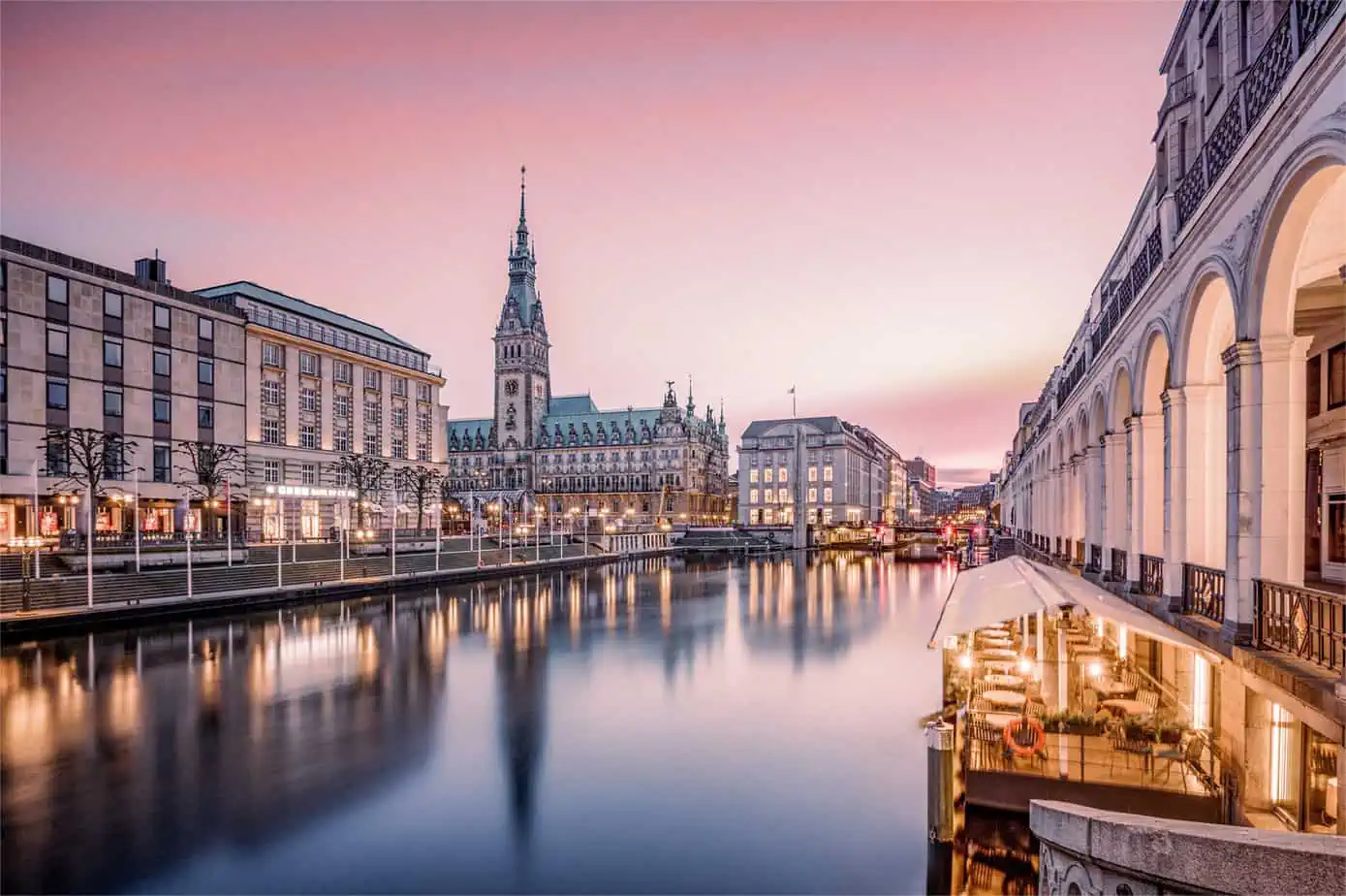 Blick auf das Hamburger Rathaus und den Alsterfleet in Abendlicht.