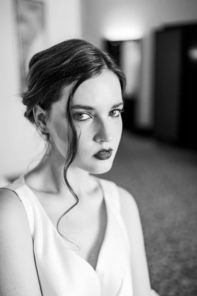 Verführerisches Schwarz-Weiß-Porträt einer eleganten jungen Frau mit intensiven Blick und kunstvollem Haarstil, aufgenommen von Artbild-Fotografie, perfekte Kombination aus Ausdruck und Stil.