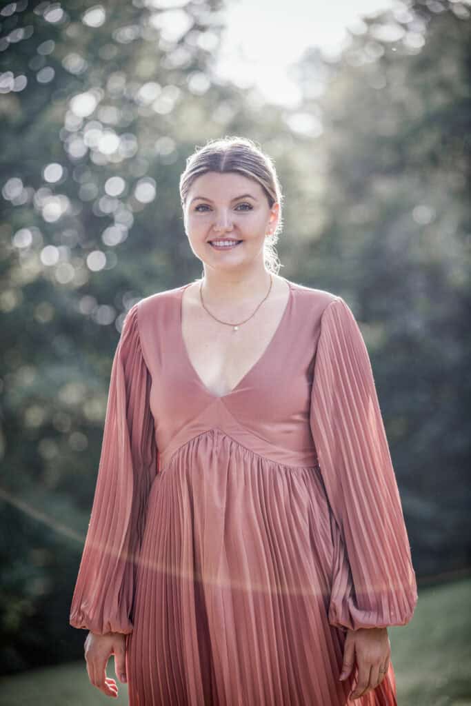 junge, blonde Frau im pastell-farbenen Kleid im Gegenlicht