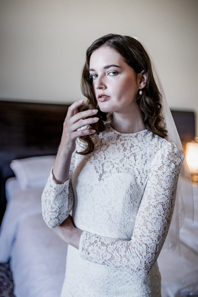 Hochzeitsfotografie Frau im eleganten Spitzenkleid mit Brautschmuck, stilvolle Bridal-Shot in Hotelzimmer, Feiern, Romantik, besondere Momente, Hochzeitsaufnahme.