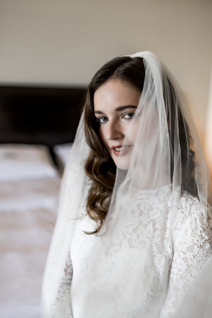 Schöne junge Braut mit Schleier und Hochzeitskleid, Portraitaufnahme in natürlichem Licht, elegante Hochzeitsfotografie, romantisches Brautbild, professionelle Hochzeitsfotografie, Artbild-Fotografie.