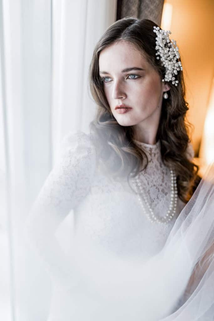 Zeitlose Hochzeitsfotografie eines eleganten Bräutigams mit Perlenhaarschmuck und Perlenkette, in einem natürlichen Licht aufgenommen. Perfekt für stilvolle Hochzeitsbilder und professionelle Hochzeitsfotografie.