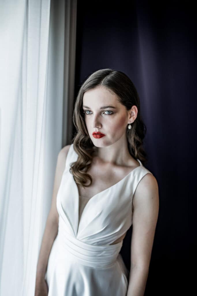 Klassische Porträtfotografie einer eleganten Frau in einem weißen Kleid vor einem dunklen und hellen Hintergrund, kreative Fotografie, professionelle Hochzeits- oder Modefotografie, Artbild-Fotografie.