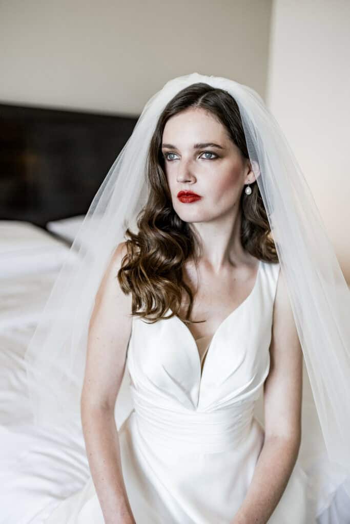 Elegante Braut mit weißem Hochzeitskleid und Schleier, natürliche Schönheit, emotionaler Moment vor der Hochzeit, professionelle Hochzeitsfotografie, stilvoll und zeitlos.