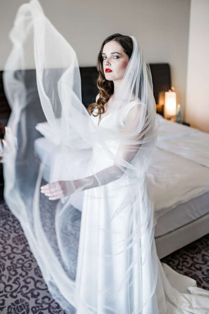 Elegante Braut in weißem Hochzeitskleid mit Tüll, glamouröses Styling, moderne Hochzeitsfotografie, Hochzeitsmesse Artbild-Fotografie.