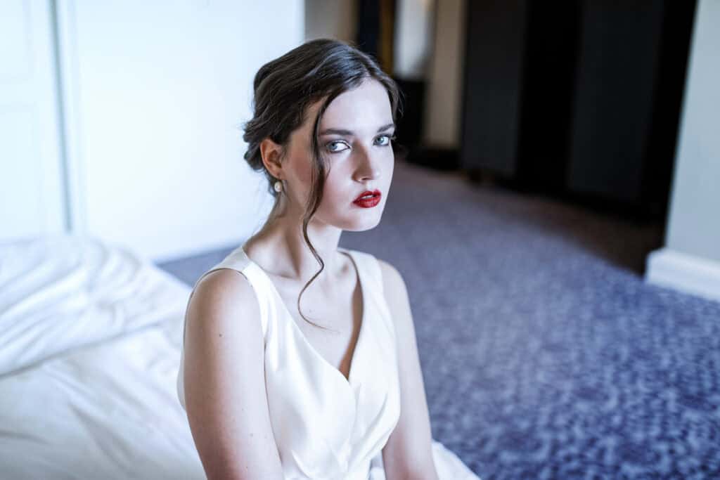 Elegante junge Frau im Vintage-Stil, Portraitaufnahme in natürlichem Licht, Fokus auf Gesicht und rote Lippen, edles Make-up, zeitlose Schönheit, professionell fotografiert für Mode- oder Beauty-Shots.